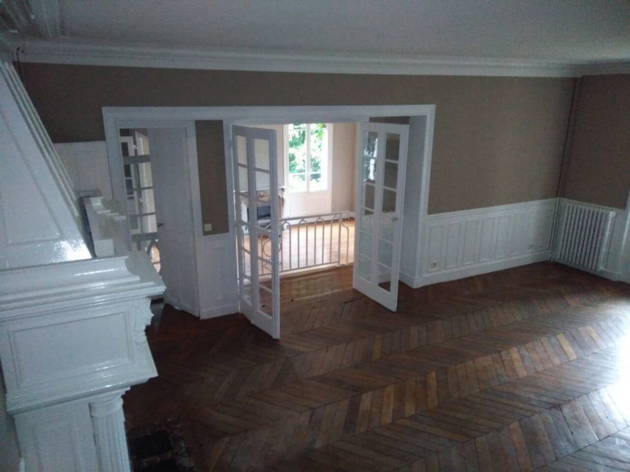 Intérieur d'une pièce vide avec des portes vitrées et un sol en parquet.