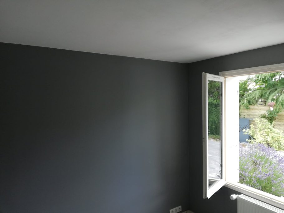 Mur gris foncé avec une fenêtre ouverte laissant entrer la lumière.