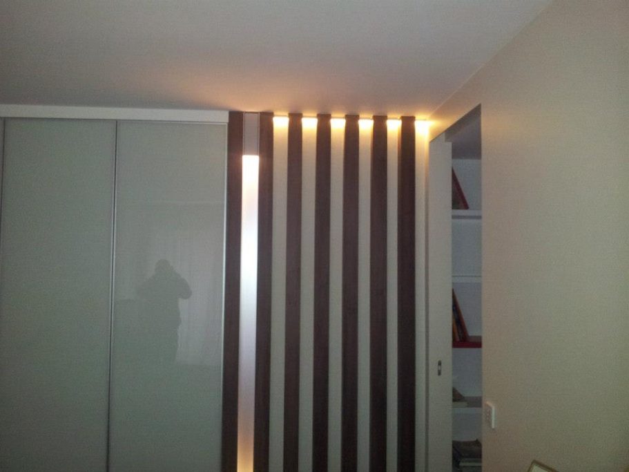 Mur avec des bandes lumineuses et une porte, décoré sobrement.